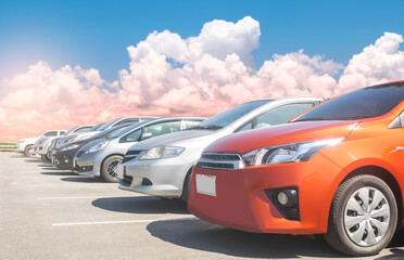 Car parked in large asphalt parking lot in a row with white cloud and blue sky background. Outdoor...