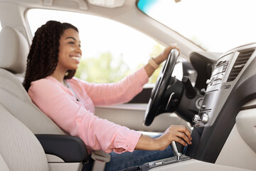 Smiling black woman driving new car in city