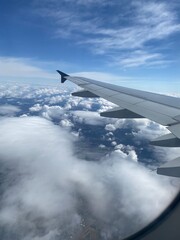 View out of airplane window - Blick aus dem Flugzeug auf Wolken von oben und die Tragfläche eines...
