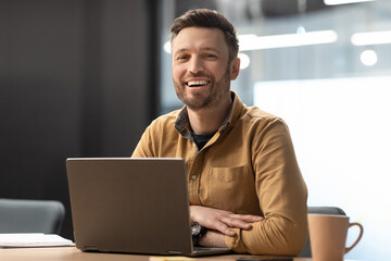 Cheerful Male Entrepreneur Posing Near Laptop Working In Modern Office