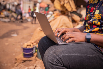 Close up of the hands of an african boy using a laptop while at the market, technology in africa