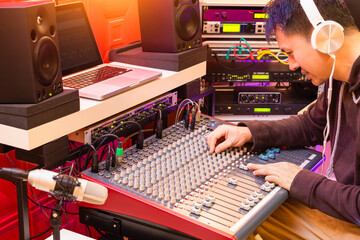 asian professional music producer working on audio mixing console in recording, broadcasting studio 
