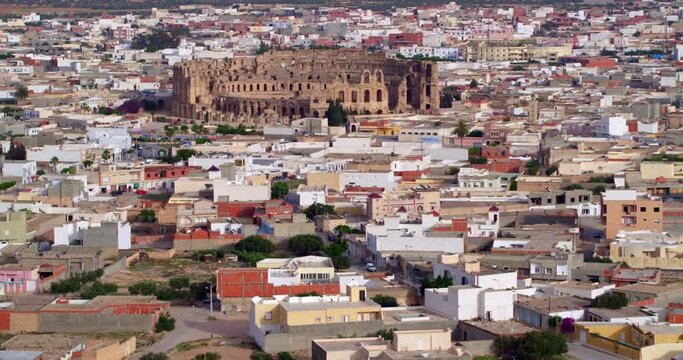 Aerial Tilt Up Shot Of Famous Dome El Jem Amphitheater In Town Against Clear Sky - El Djem, Tunisia