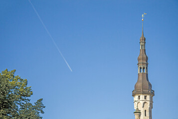 Fototapeta na wymiar Old town hall tower and jet contrail. Tallinn, Estonia