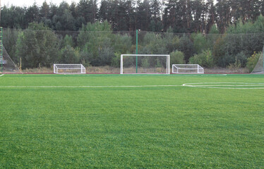 Football field with green lawn.
Sports floor for outdoor play.
Professional surface for street football. Beautiful grass in the sun. White marking of the territory.
Concept: street sports, street game