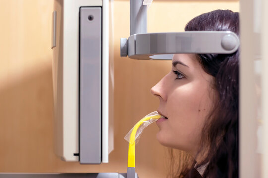 Side close-up of a young woman having a panoramic x-ray of her mouth in a dental clinic