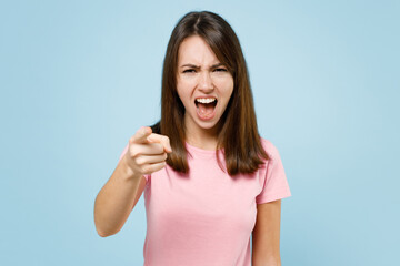 Fototapeta premium Young sad abuser angry caucasian woman 20s wearing pink t-shirt point index finger camera on you scream shout isolated on pastel plain light blue background studio portrait. People lifestyle concept.