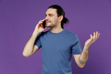 Young smiling man 20s wearing basic blue t-shirt talk speak on mobile cell phone conducting...
