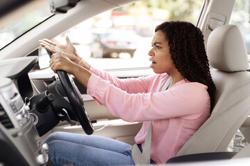 Angry black woman driving car shouting at somebody