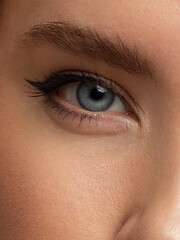 Glamour close-up portrait of beautiful woman model face with winged black eyeliner make-up, clean skin on white background. Long eyelashes and thick eyebrows.
