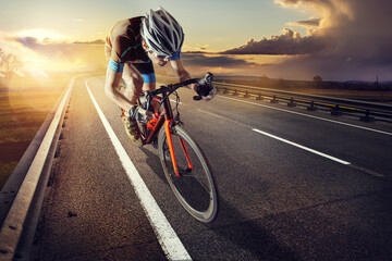 The cyclist rides on his bike at sunset. Dramatic background. - obrazy, fototapety, plakaty