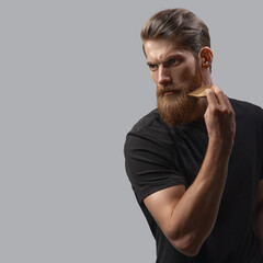 Bearded man with hair brush. Trendy and stylish beard styling and cut. Brutal young bearded man....