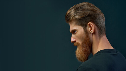 Dramatic concept portrait of a young handsome bearded man looking ahead. Perfect beard. Copy free...