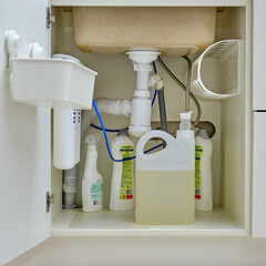 Detergents and cleaning products under the sink in the white kitchen cabinet