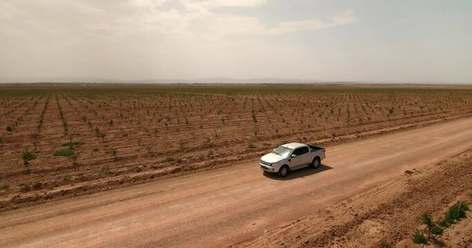 Aerial Panning Shot Of Pull Up Truck Parked On Road In Field During Sunny Day - Djerba, Tunisia