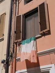 A faded and battered Italian flag flutters from a window.