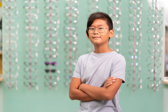 An asian boy trying on glasses in an optician store.