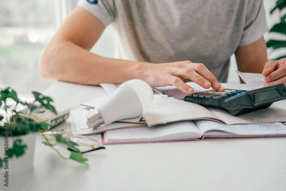 Wall mural a man counts a bill on a calculator and a check for electricity on the table. payment of utility ser