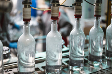 Equipment pours vodka into glass bottles on production line