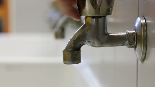 hand closing the water tap in the sink to avoid waste