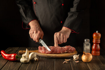 The chef cuts raw veal meat on a cutting board before barbecue. Asian cuisine. Cooking delicious food in the kitchen.