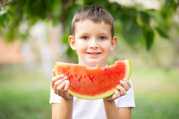 Cute boy eating watermelon outdoors in summer. Healthy eating seasonal berries and fruits