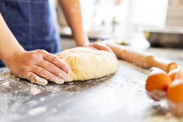Female hands making dough for baking on wooden table near rolling pin, eggs and milk bottle. Culinary, cooking, baking concept