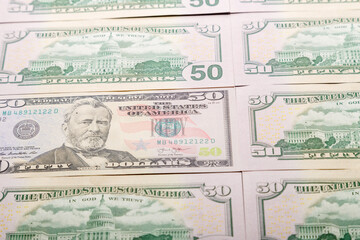 Close-up of fifty dollar bills spread out on the table.