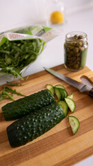 Fresh cucumbers are cut by the knife on the table.