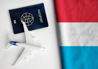 Flag of Luxembourg with passport and toy airplane. Flight travel concept  - obrazy, fototapety, plakaty