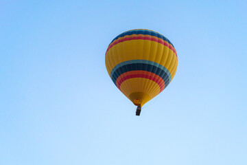 Fototapeta na wymiar Colorful balloon flying over Cappadocia with a clear cloudless sky, copy space