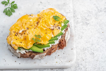 Scrambled eggs with avocado and cream cheese on toast