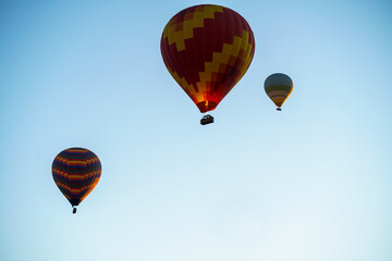Balloons burning fuel as they fly over the city of Goreme with sightseeing tourists during a sunny summer day