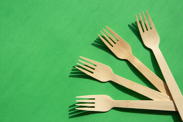 Wooden bamboo cutlery on bright green background