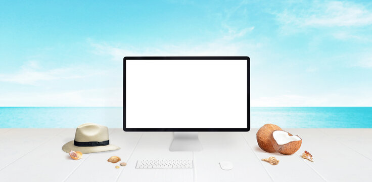 Computer display mockup on desk with beach in background. Isolated screen for mockup. Traveler hat, coconuts and shells beside. Travel concept
