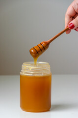 closeup shot on honey pot and wooden honey spoon