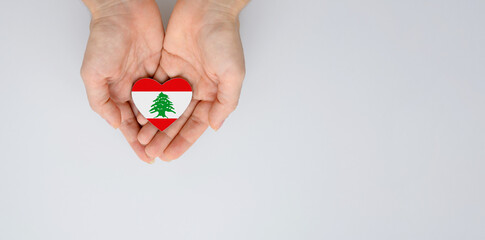 The national flag of Lebanon of arms in female hands. Flat lay, copy space.