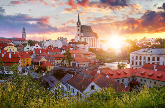Czech Krumlov, Czech Republic. Scenic Panorama of old town with view at roofs of houses and saint vitus cathedral. Evening sunset landscape. Sky with sunlight and clouds.