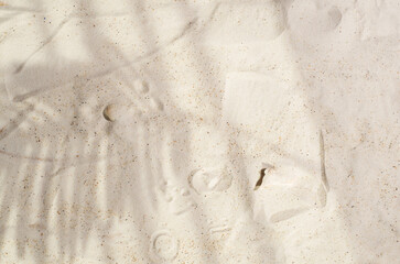 An empty background for product display, for marketing. Sand with hard leaf shadows,