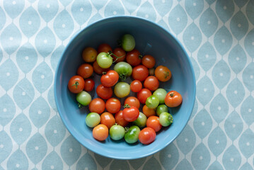 Fresh green and red tomatoes in a bowl.