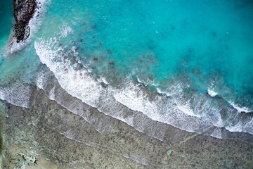 Drone field of view of waves crashing into beach and sand in tropical island paradise of Seychelles.