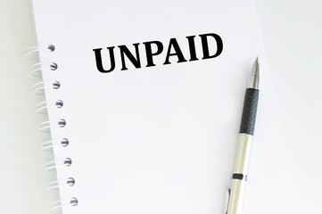 Unpaid inscription on a notebook on the table next to the pen, a business concept