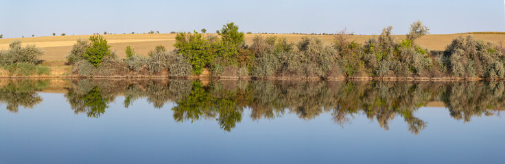Landscape with trees, reflecting in the water.