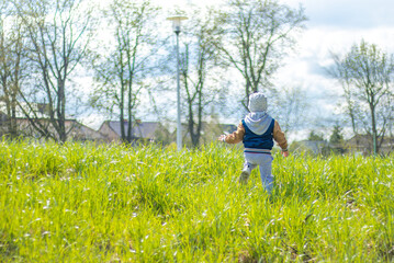 Mały chłopczyk biegnący po pięknej zielonej łące.
