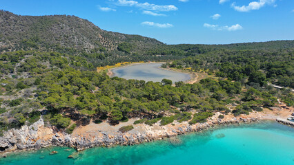 Aerial drone photo of iconic Aponisos bay and lake with clear turquoise sea and pine trees,  Agistri island, Saronic gulf, Greece