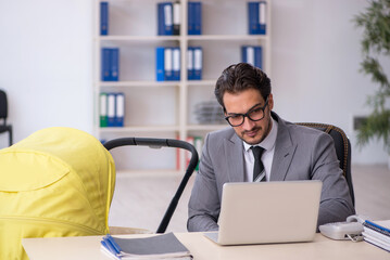 Young male employee looking after new born at workplace