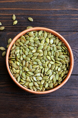 Pumpkin seeds in a wooden spoon on a wooden background. Healthy food. Scattered seeds of pumpkin. Copy space