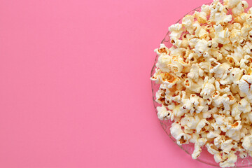 a plate of popcorn on romantic pink background close up, copy space