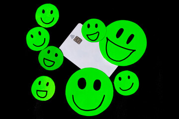 Illustration of smiling emoticons with a white credit card on black background. Concept of acceptance of card payment, use of credit card, happiness of payment system. Ease of shopping.