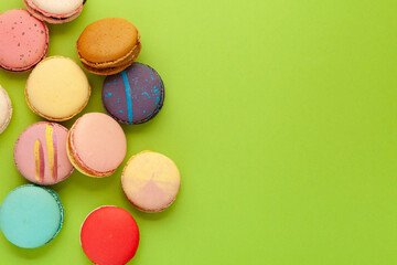 Fototapeta na wymiar Macarons or macaroons with different flavors on green background. Flat lay, copy space